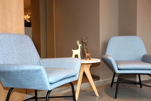Two light blue chairs with wooden legs and a small round table with a decorative deer sculpture between them. - Home Inn (Weihai Kunming Road Tourist Dock Weigao Plaza) (Weihai)