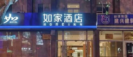 A hotel entrance with a sign reading "Home Inn" and another sign indicating a group of hotels.