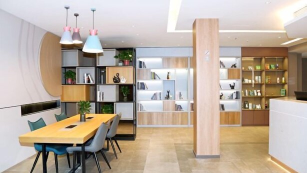 A modern kitchen with a wooden dining table, chairs, pendant lights, and built-in shelving with books and decorative items. - Home Inn (Weihai Kunming Road Tourist Dock Weigao Plaza) (Weihai)