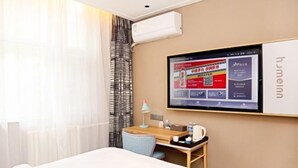 A hotel room with a bed, a desk with a lamp, a TV mounted on the wall, and an air conditioning unit. - Home Inn (Weihai Kunming Road Tourist Dock Weigao Plaza) (Weihai)