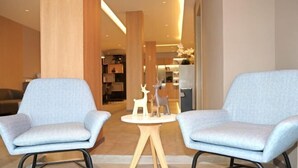 Two light grey armchairs facing a small round wooden table with a white top. The room has a modern design with wooden accents and a neutral color palette. - Home Inn (Weihai Kunming Road Tourist Dock Weigao Plaza) (Weihai)