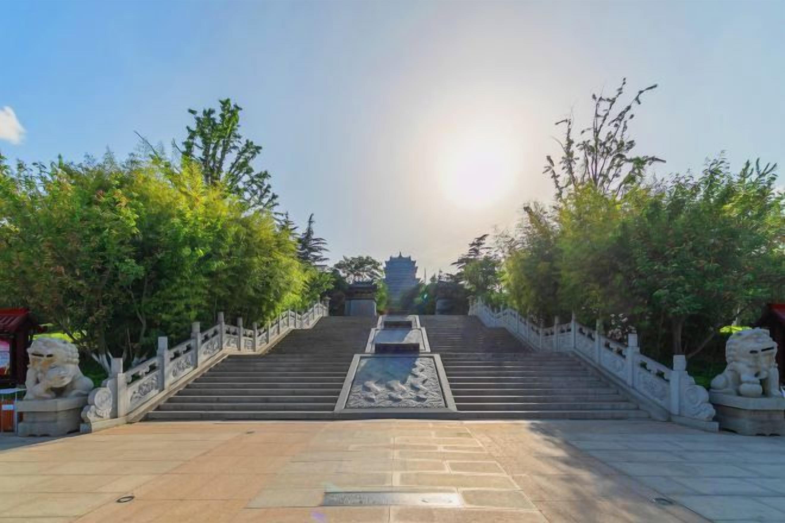 Una escalera conduce a un templo, con barandillas de piedra y estatuas a ambos lados.