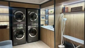 A laundry room with two wall-mounted washing machines, a sink, and a drying rack. - Home Inn (Weihai Kunming Road Tourist Dock Weigao Plaza) (Weihai)