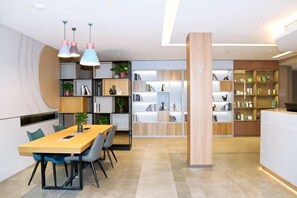 Una zona menjador moderna amb taula i cadires de fusta, una prestatgeria i llums penjants.