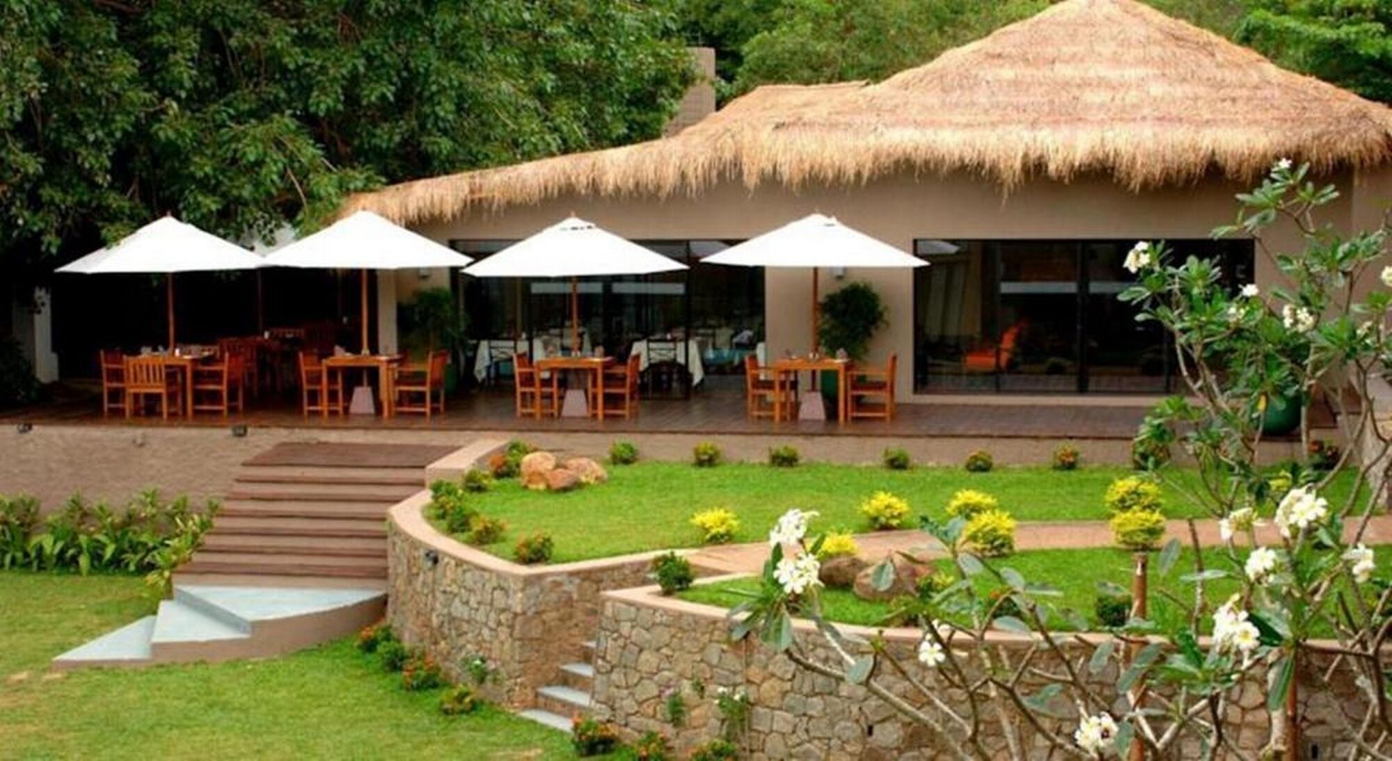 A thatched-roof building with outdoor seating and a stone pathway.
