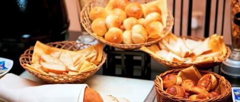Una mesa de buffet con panes y pasteles varios.