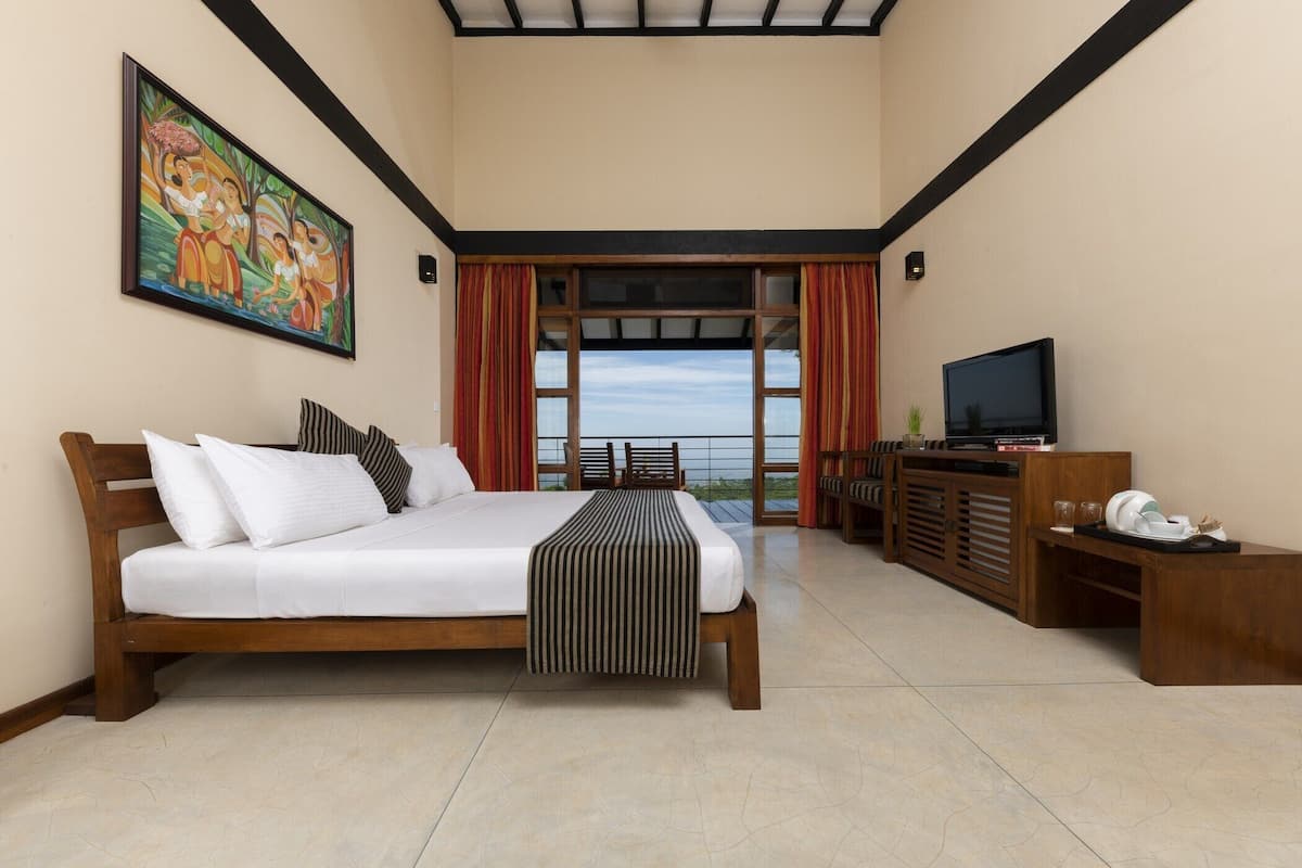 A bedroom with a bed, a television, a wooden cabinet, and a painting on the wall.