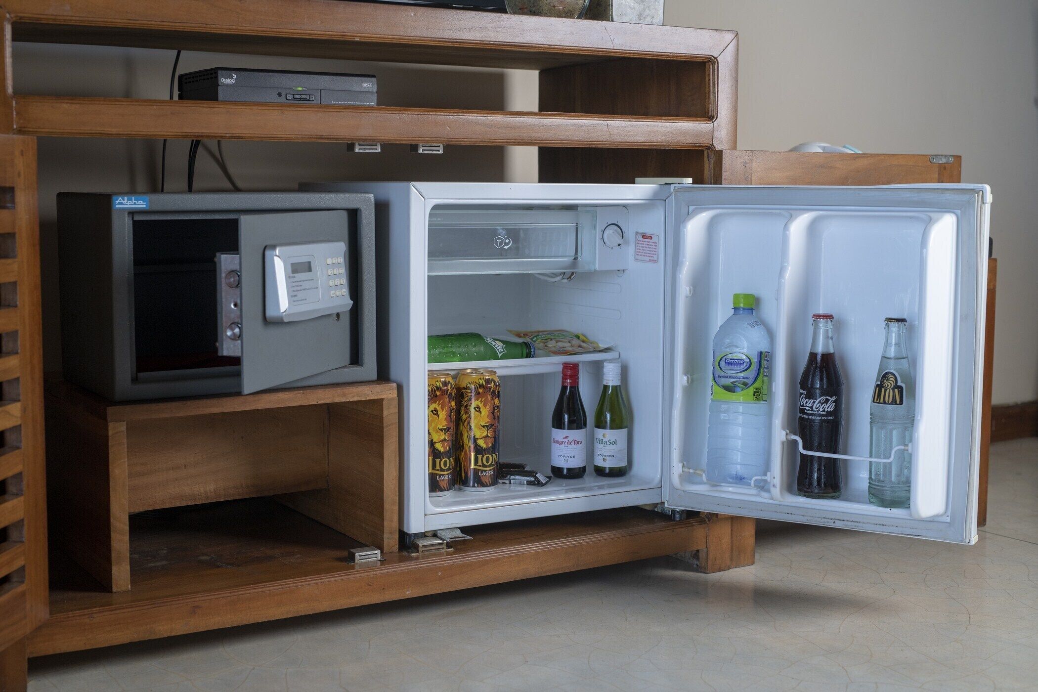 A compact refrigerator with a digital control panel, containing beverages and snacks.