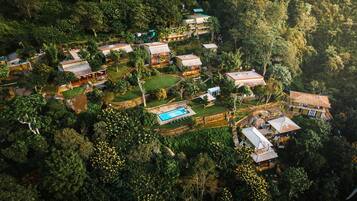 An aerial view of a residential area with multiple houses surrounded by dense greenery.