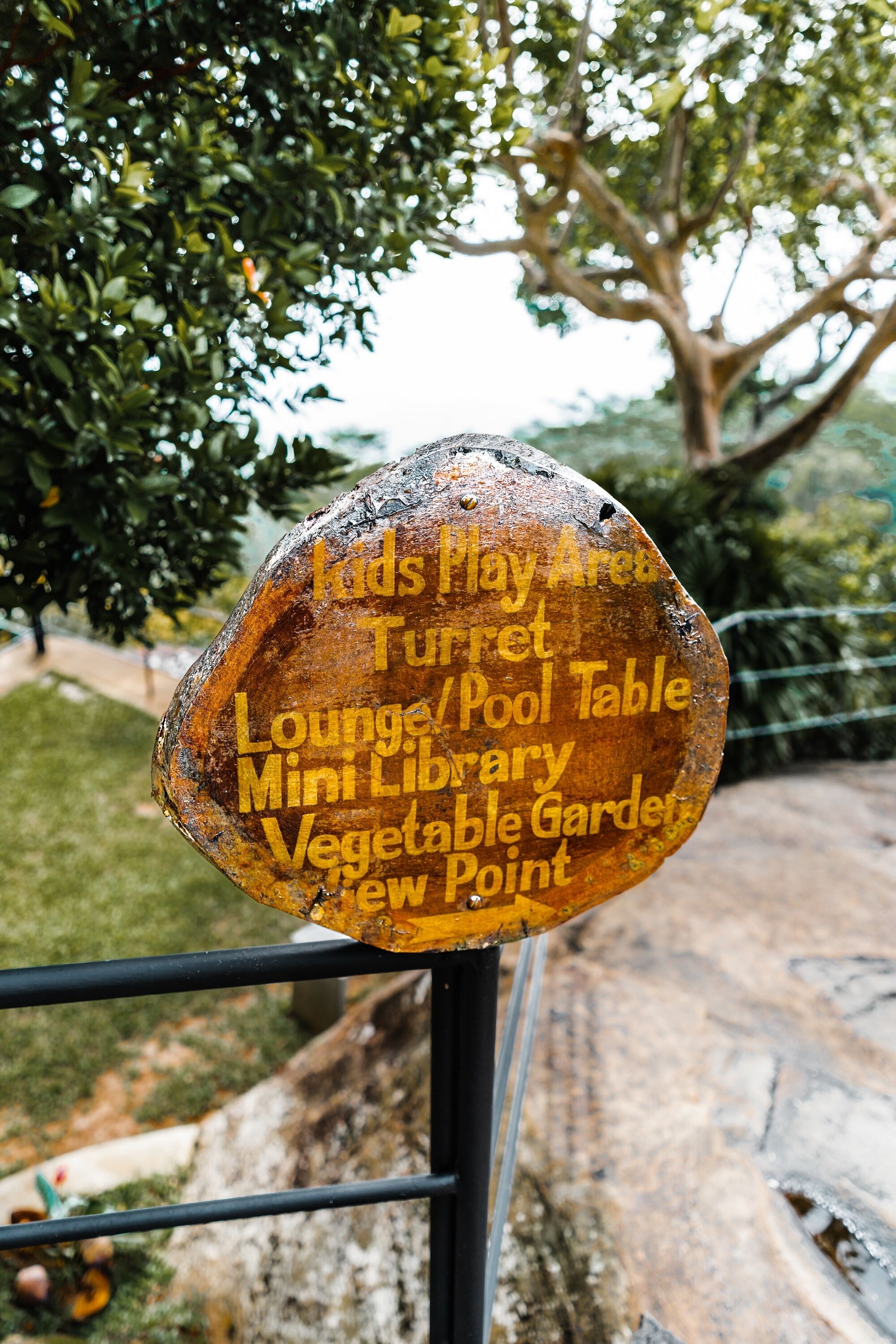 Un cartel que enumera servicios como zona infantil, torre, sala de estar/billar, pequeña biblioteca, huerto y mirador.