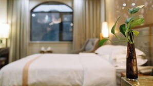 A hotel room with a bed, a bedside table with a plant, and a window with curtains. - Yuanfeng Hebei Hotel (Lhasa)