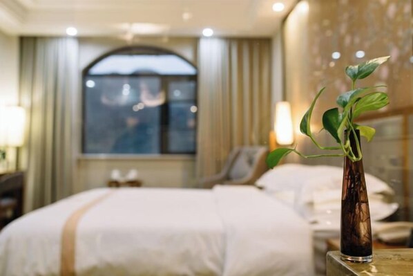 A hotel room with a bed, a bedside table with a plant, and a window with curtains. - Yuanfeng Hebei Hotel (Lhasa)