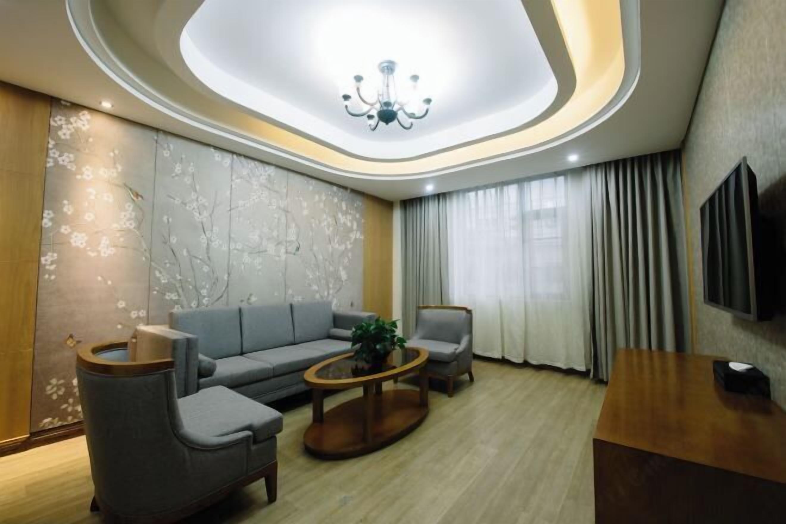A modern living room with a sofa, armchairs, a coffee table, and a TV mounted on the wall.