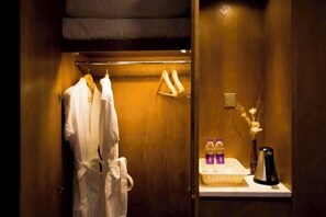 A hotel bathroom with a wooden vanity, a robe hanging on a rack, and toiletries on the counter. - Yuanfeng Hebei Hotel (Lhasa)