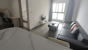 Une chambre d’hôtel moderne équipée d’un lit, d’un bureau avec une lampe, d’une télévision, d’une table basse et d’un canapé avec un coussin.