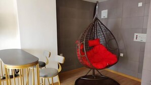 Une pièce moderne avec un fauteuil suspendu, une table à manger et un canapé.