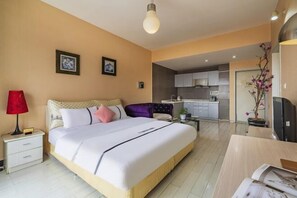 Quarto moderno com uma cama grande, mesas de cabeceira, uma escrivaninha e vista para a cozinha.