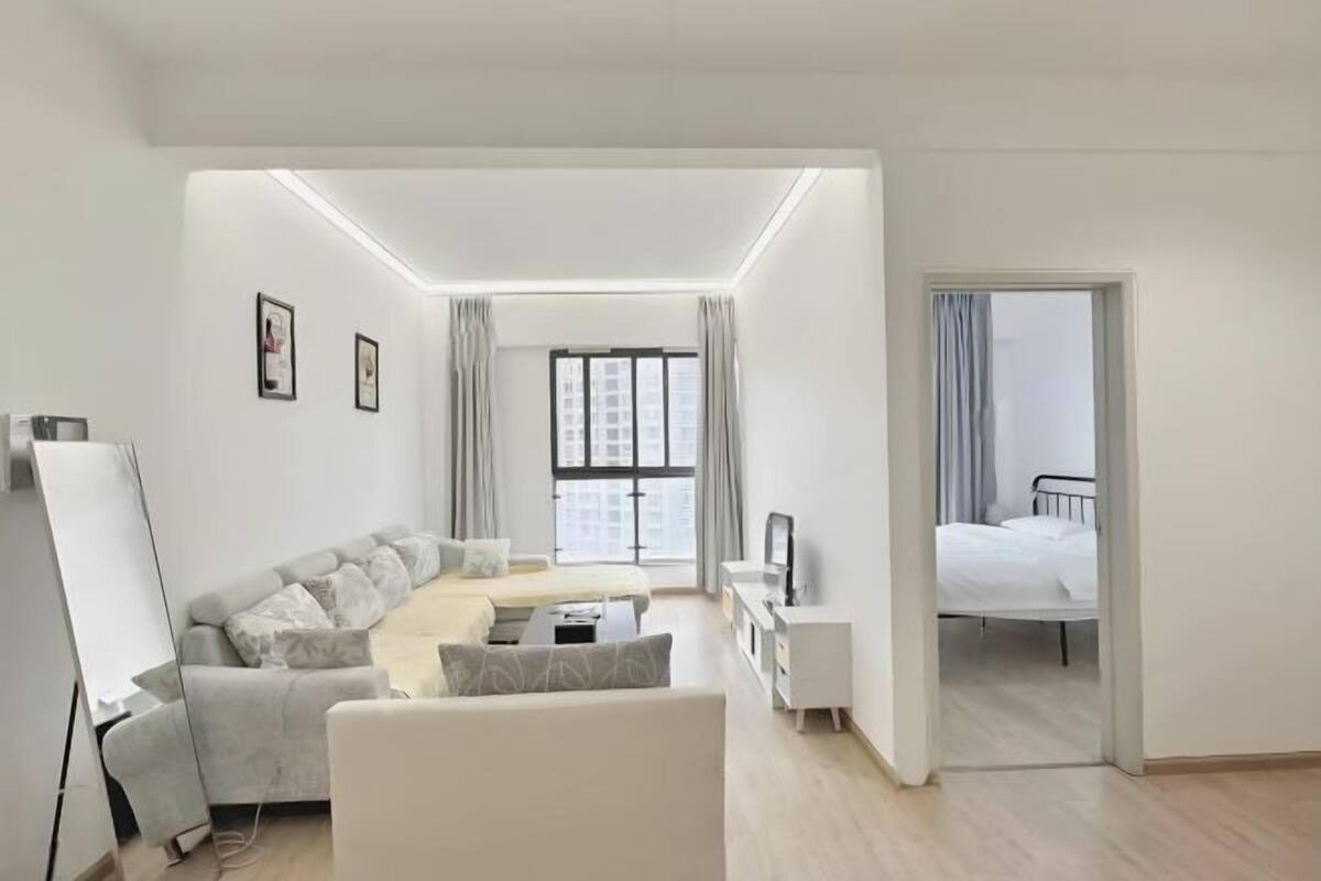 A modern hotel room with a sofa, a bed, a desk, and a TV.