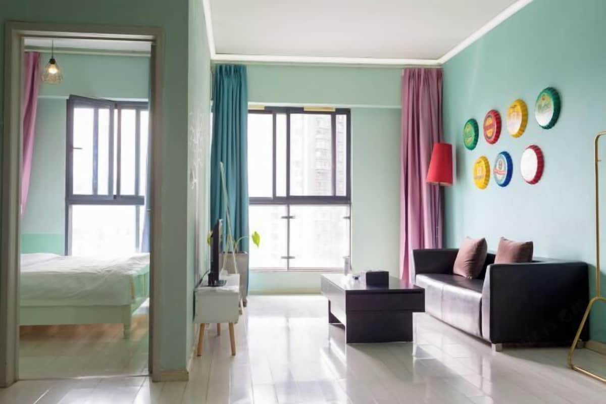 Uma sala de estar moderna com sofá, mesa de centro e escrivaninha. Há cortinas nas janelas e uma luminária sobre a escrivaninha.