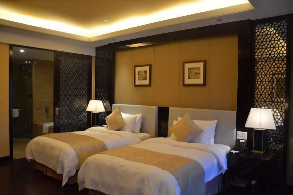 A hotel room with two beds, a large mirror, and a decorative wall panel.