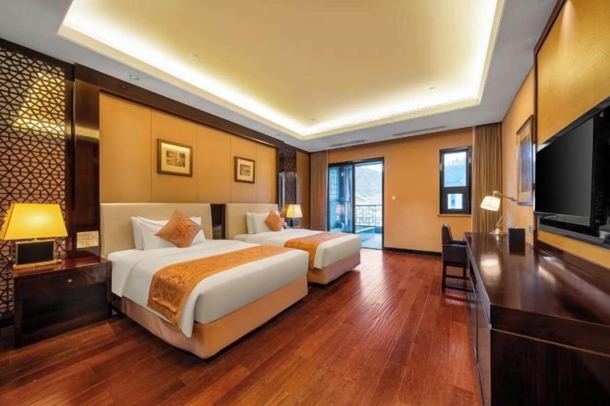 Une chambre d’hôtel avec deux lits, une télévision et un balcon.