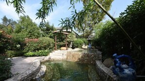 A tranquil garden with a stone-lined pond, a wooden gazebo, and lush greenery. - Ming Resort & Spa (Yuyao)