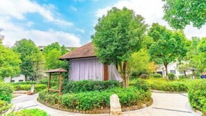 A traditional building with a tiled roof, surrounded by lush greenery and a stone pathway. - Ming Resort & Spa (Yuyao)