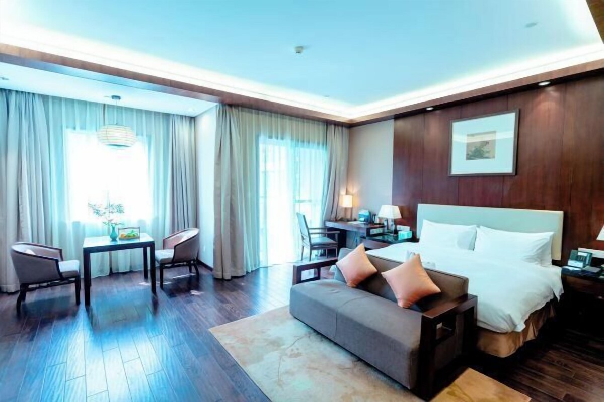 A hotel room with a bed, a sofa, a desk, and a chair.