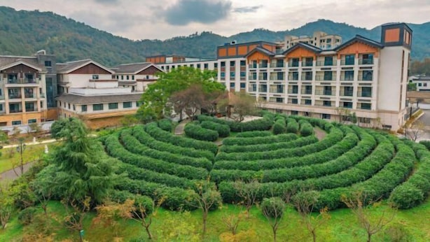 A hotel with a circular garden and a mountainous backdrop. - Ming Resort & Spa (Yuyao)
