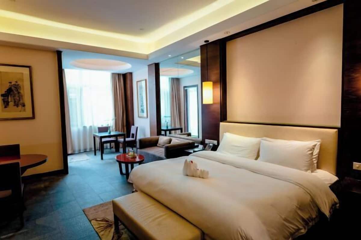A hotel room with a large bed, a desk, a chair, and a sofa.