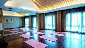A spacious room with wooden flooring, large windows with curtains, and pink yoga mats arranged for exercise. - Ming Resort & Spa (Yuyao)