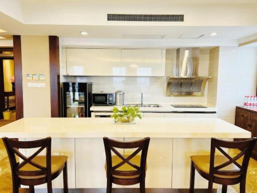 A modern kitchen with a central island, two bar stools, and a stainless steel range hood.