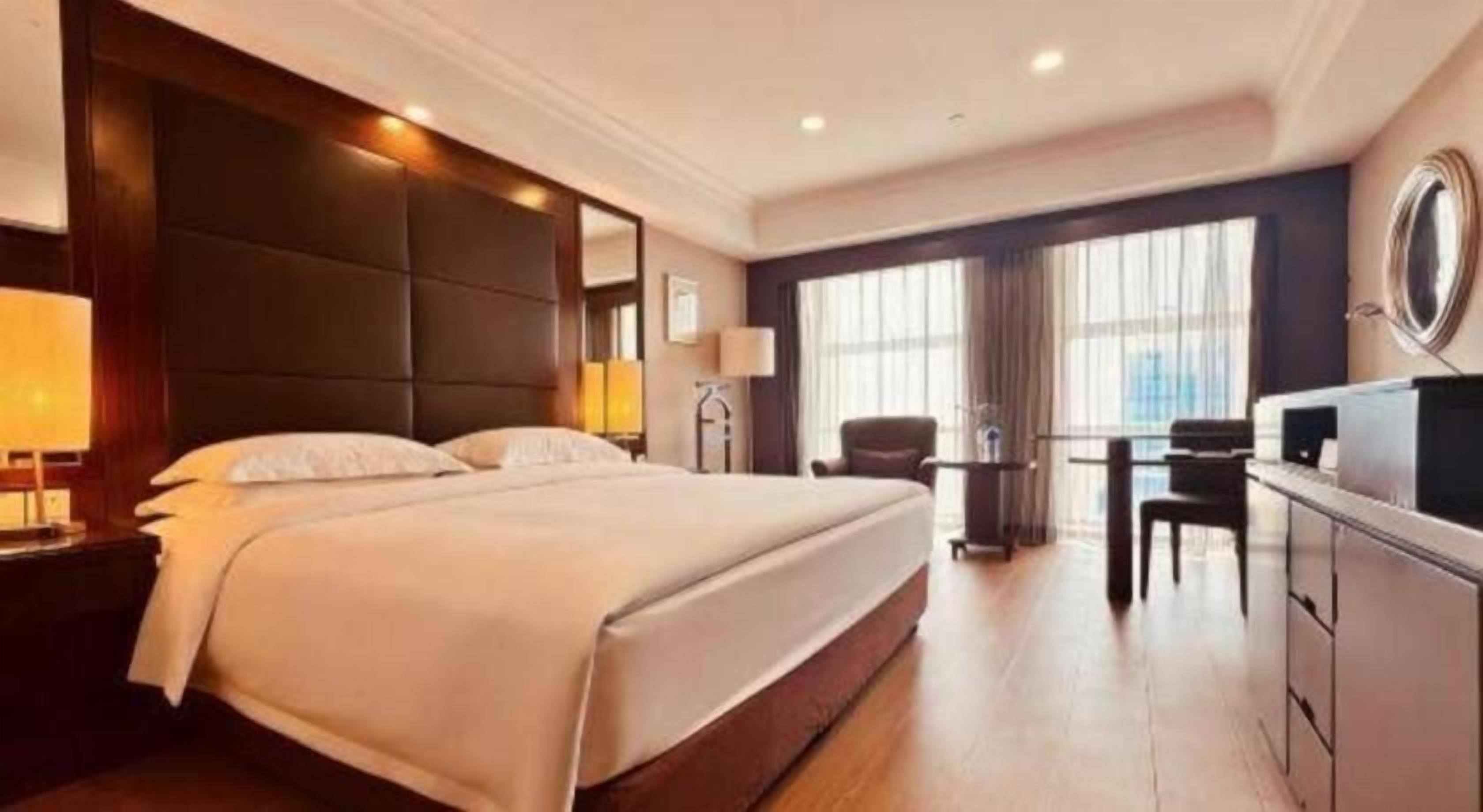 A hotel room with a large bed, a desk, and a chair.