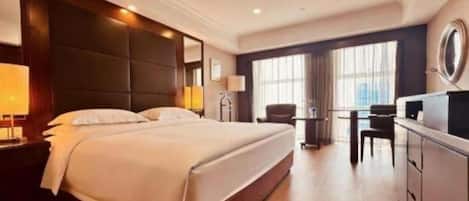 A hotel room with a large bed, a desk, and a chair.