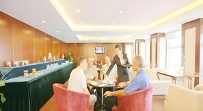 A hotel lobby with a reception desk, seating area, and a television screen. - Marco Polo Garden Hotel (Hangzhou)