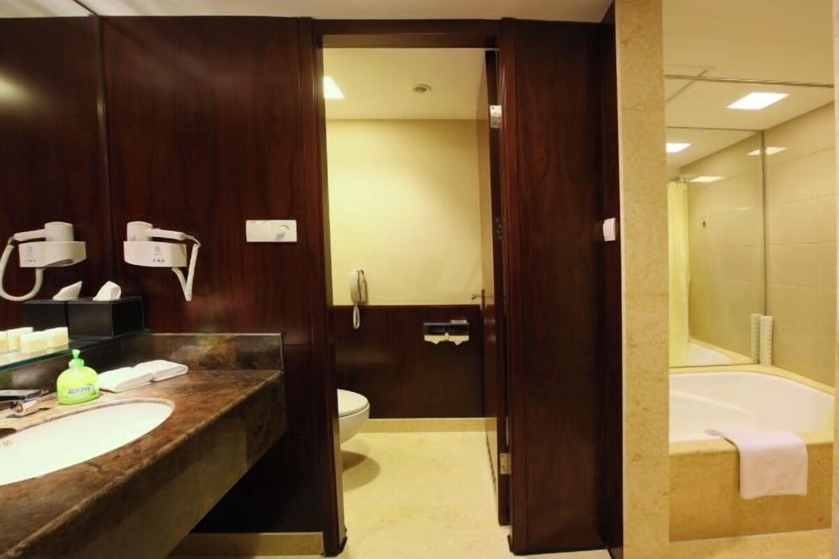 Une salle de bain avec un lavabo en marbre, des toilettes, une baignoire et un miroir.