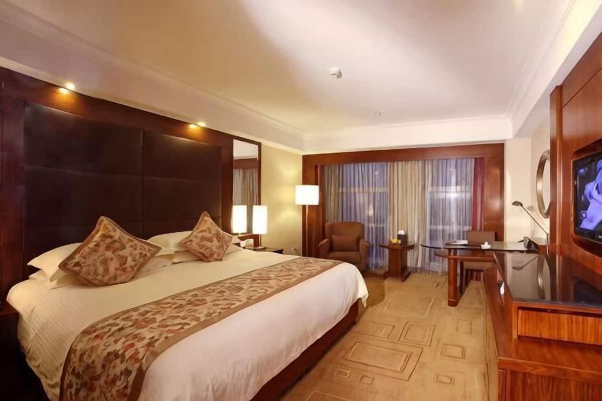 Une chambre d’hôtel avec un grand lit, une télévision, un bureau et une chaise.
