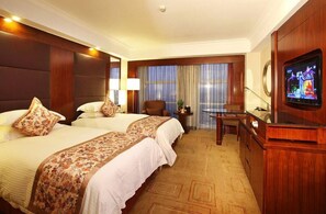 Une chambre d’hôtel avec deux lits, une télévision, un bureau et une chaise.