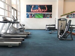 Een fitnessruimte met loopbanden, krachtapparaten en gewichten.