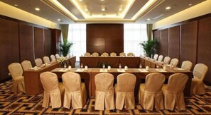 Une salle de conférence avec une longue table et des chaises, une grande fenêtre et un sol recouvert de moquette.
