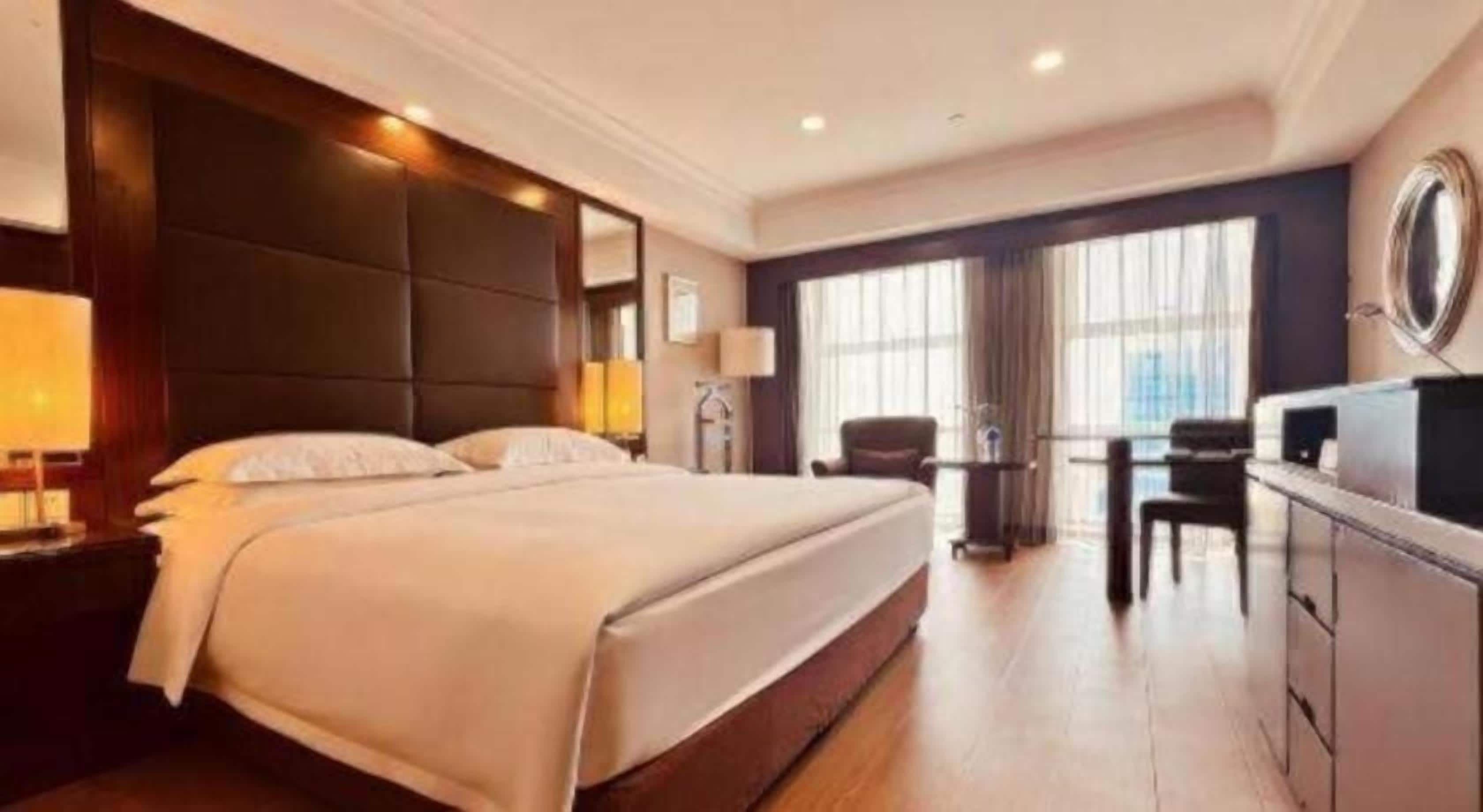 A hotel room with a large bed, a desk, and a chair.