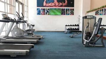 Uma academia com esteiras, aparelhos de musculação e halteres.