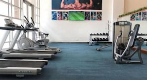 Uma academia com esteiras, aparelhos de musculação e halteres.