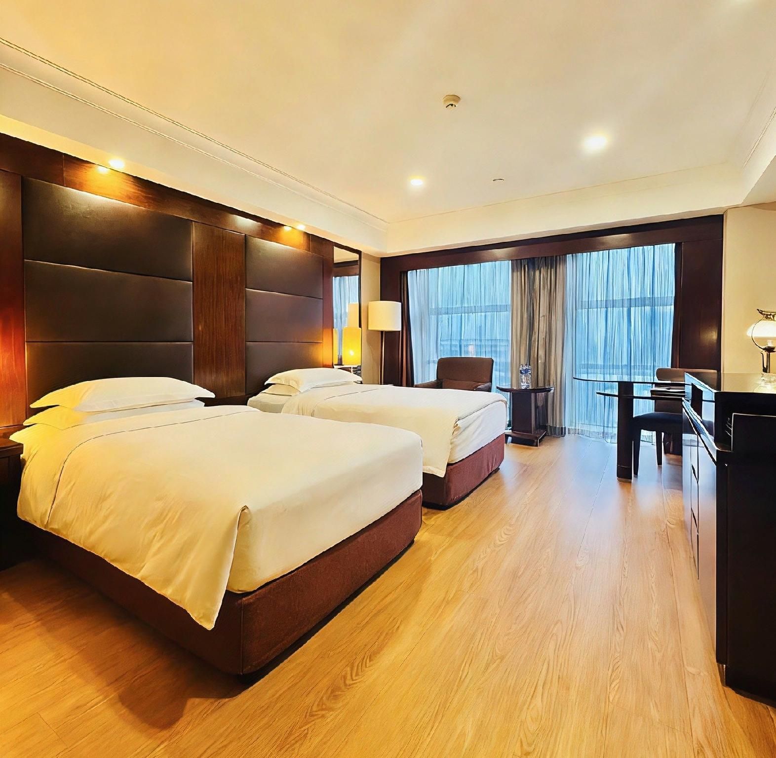 A hotel room with two beds, a desk, and a chair.