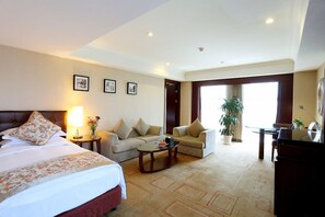 Ein Hotelzimmer mit einem Bett, zwei Sofas, einem Couchtisch, einem Schreibtisch und einem großen Fenster.