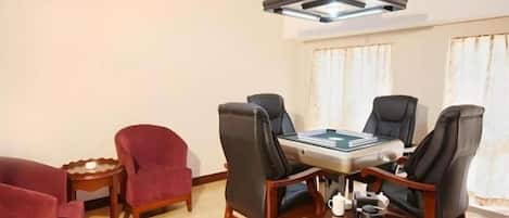 A room with a round table, four chairs, a small side table, and a red armchair.