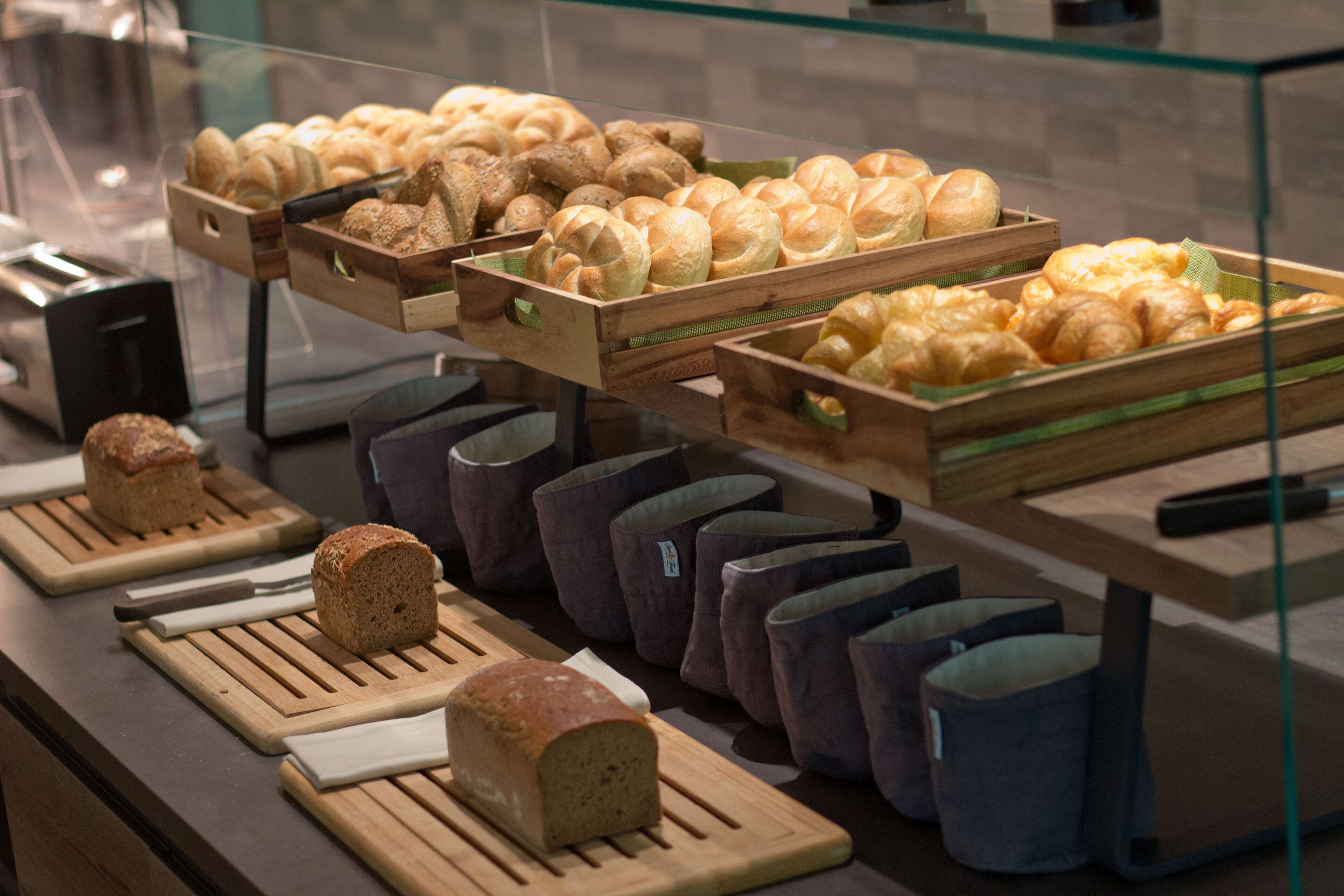 A bakery display with various breads and pastries in wooden crates and baskets.