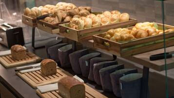 A bakery display with various breads and pastries in wooden crates and baskets.