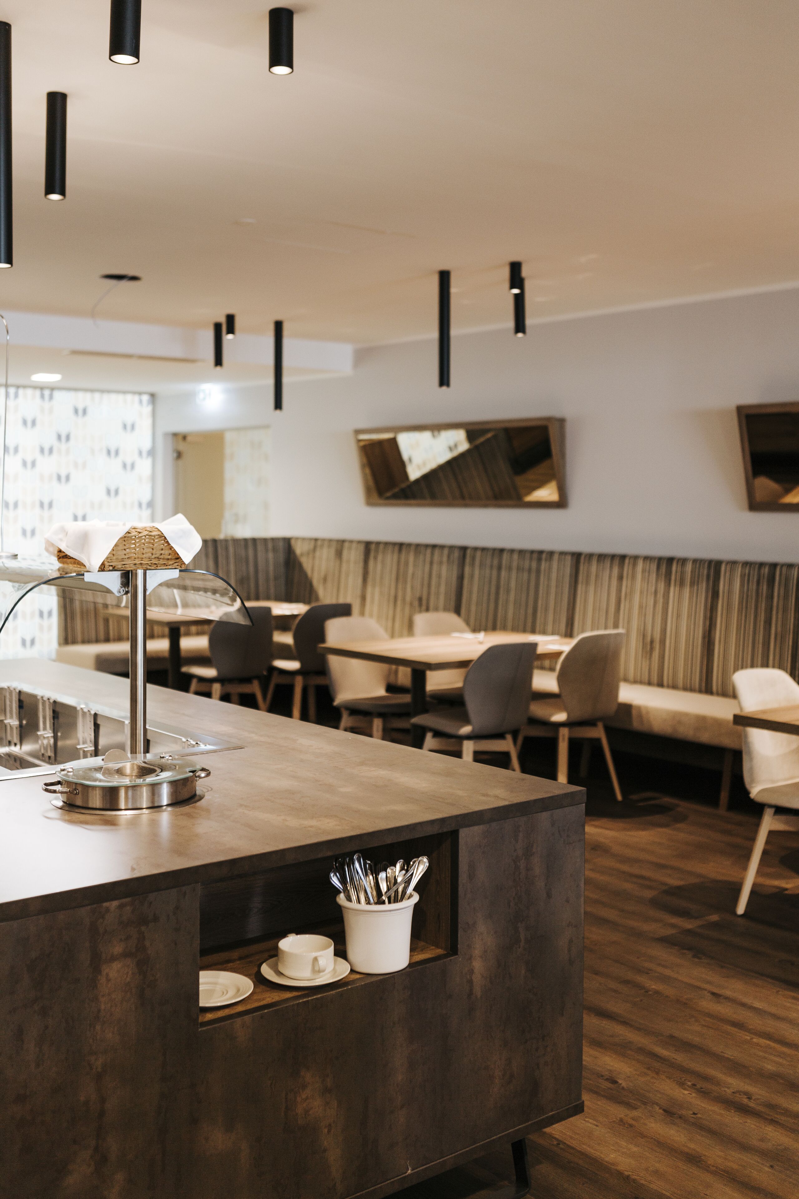 A modern restaurant with a central island, seating area, and contemporary lighting.