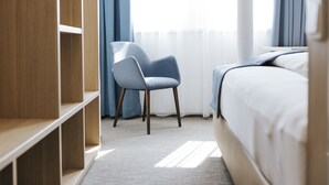 A hotel room with a bed, a chair, a wardrobe, and a window with curtains. - Sankt Magdalena (Linz)